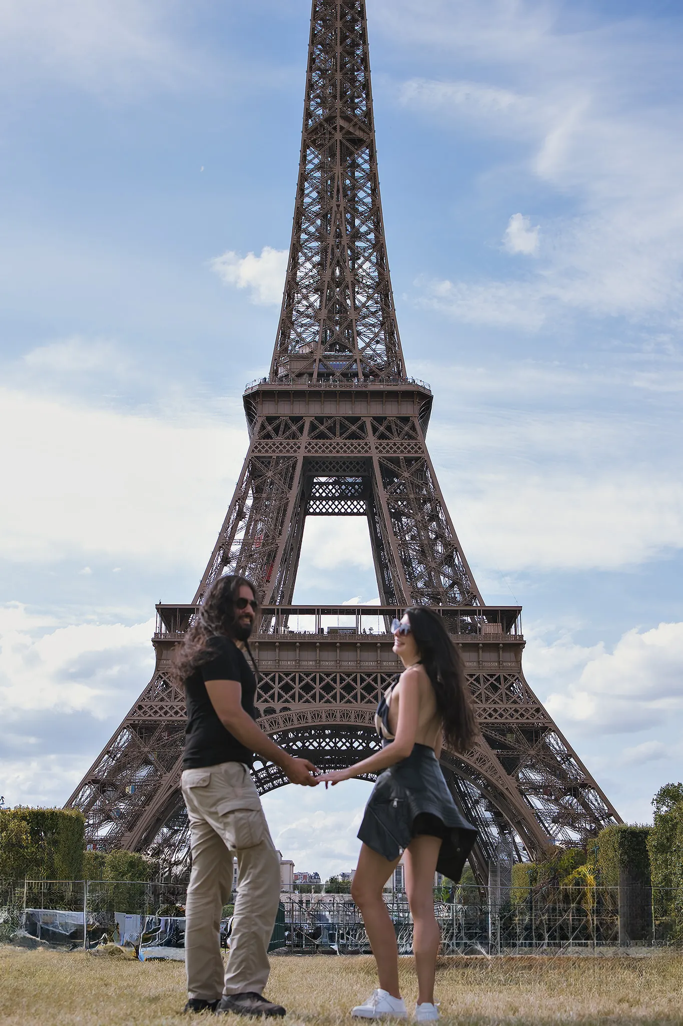 Victor e Joyce de mãos dadas diante da Torre Eiffel