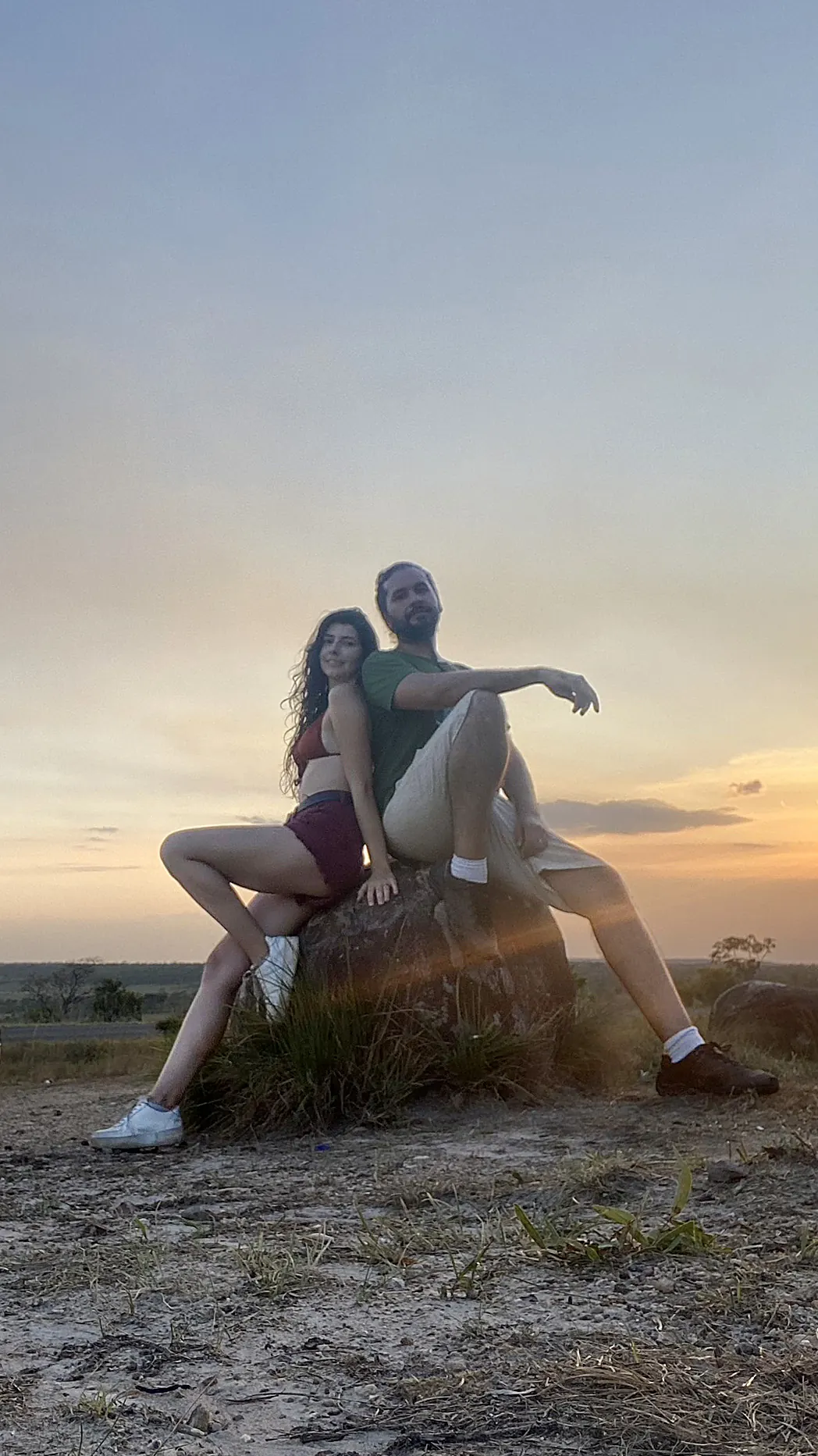 Victor e Joyce sentados numa pedra ao pôr do sol
